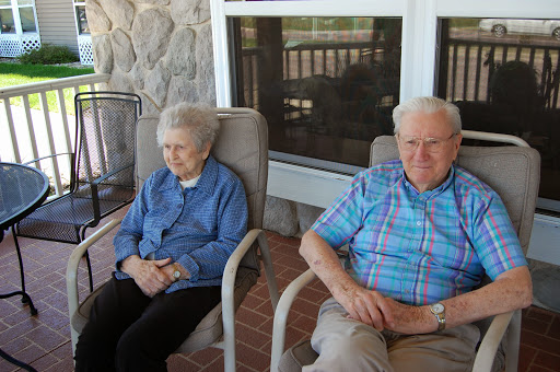 A serene moment shared by an elderly couple on their porch.