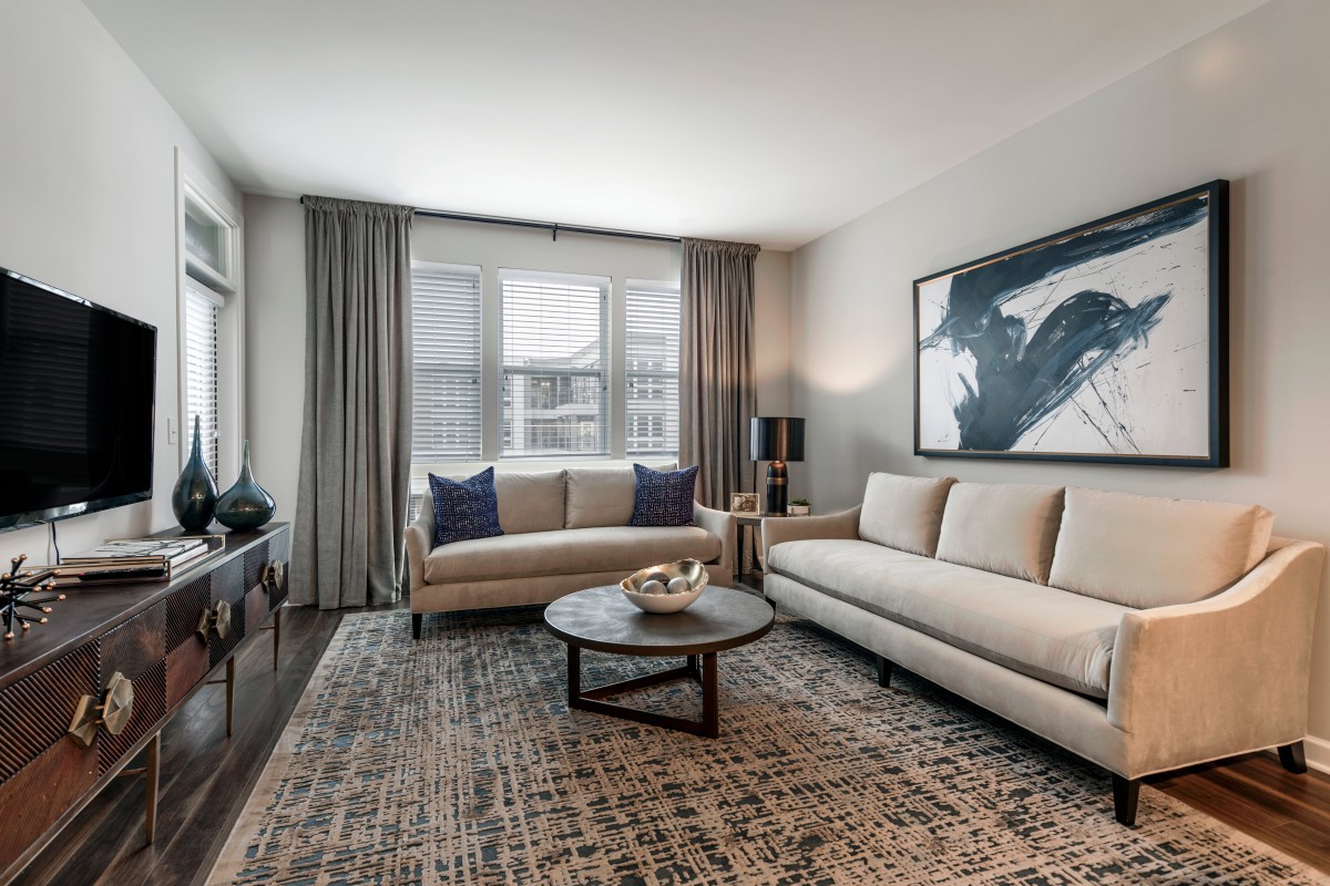 A modern living room with two beige sofas, a central coffee table, and abstract artwork on the wall.