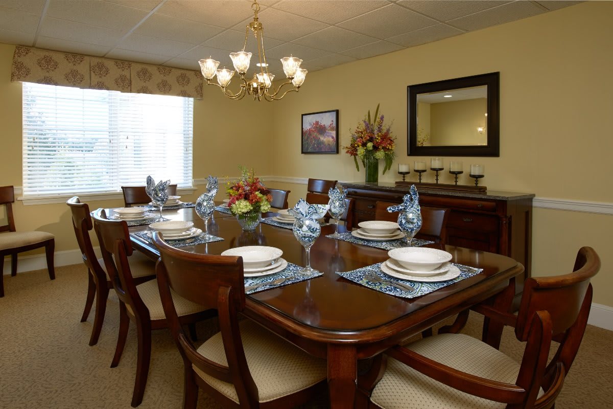 A well-arranged dining room featuring an elegant table setting with a chandelier above.