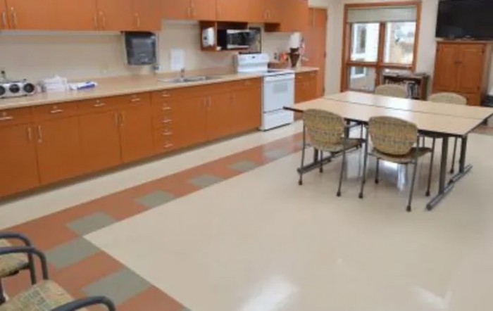 A spacious kitchen with wooden cabinets, a table and chairs, and various appliances.
