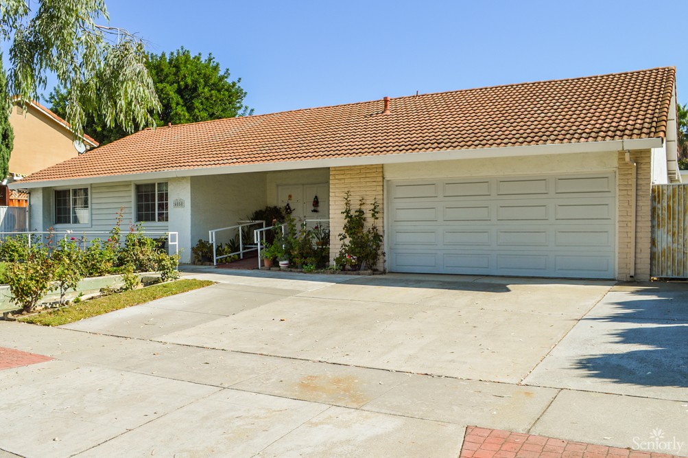 A suburban house with a two-car garage and a driveway under a clear blue sky.