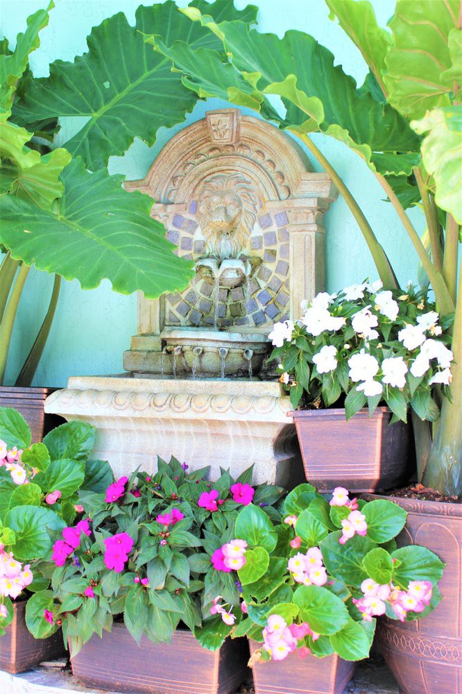 A serene garden fountain surrounded by vibrant flowers and lush greenery.