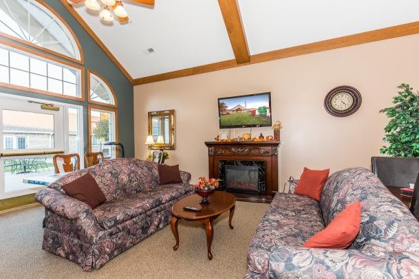 A cozy living room featuring a fireplace and floral patterned sofas with a mounted television above the mantel.