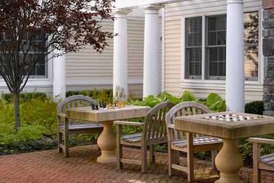 A cozy outdoor patio with tables and chairs surrounded by greenery.