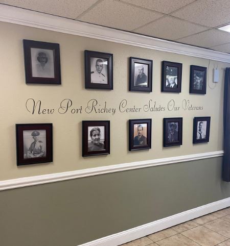 A hallway features a collection of framed black and white photos arranged in two rows, accompanied by elegant script text on the wall.