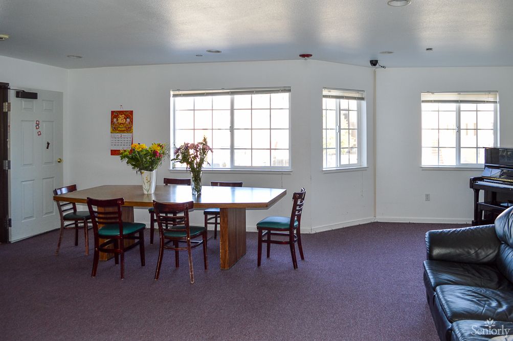 A simple dining area with a table, chairs, and flowers near large windows.