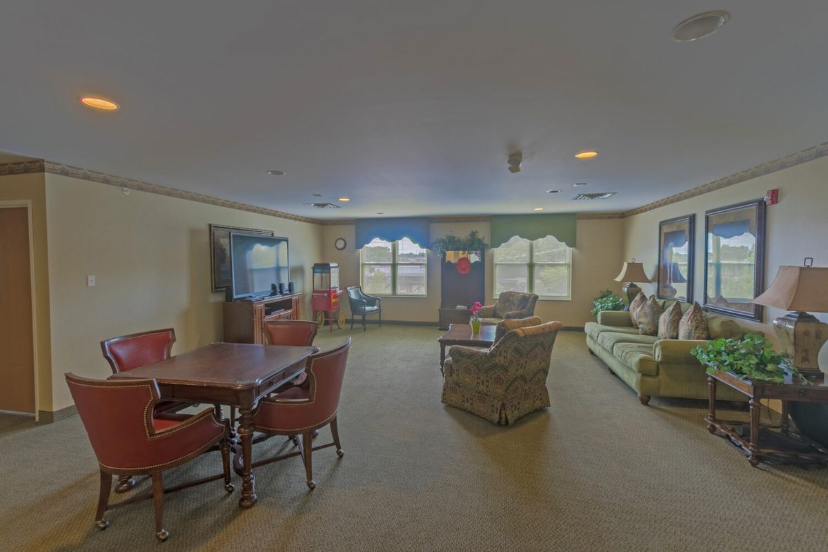 A cozy living room featuring comfortable seating, a television, and large windows allowing natural light.