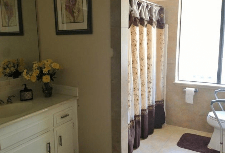 A cozy bathroom with a floral shower curtain and decorative elements.