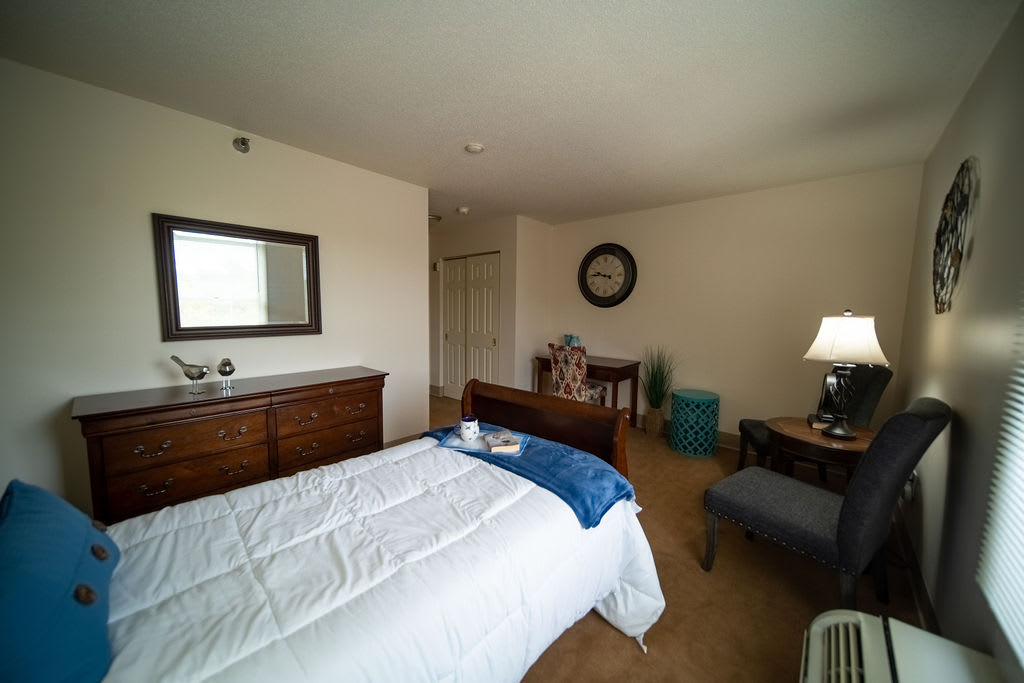 A cozy bedroom with a bed, dresser, and various furnishings.