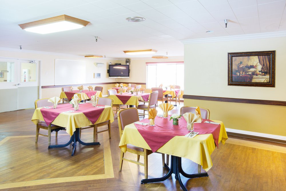 A bright dining area with neatly arranged tables and chairs, featuring vibrant tablecloths.