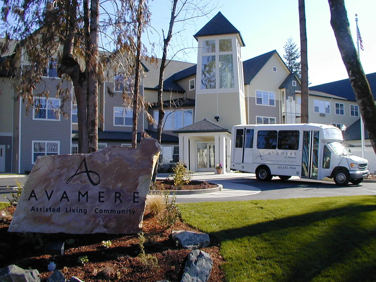 A scenic view of a building with a sign and a shuttle bus parked outside.