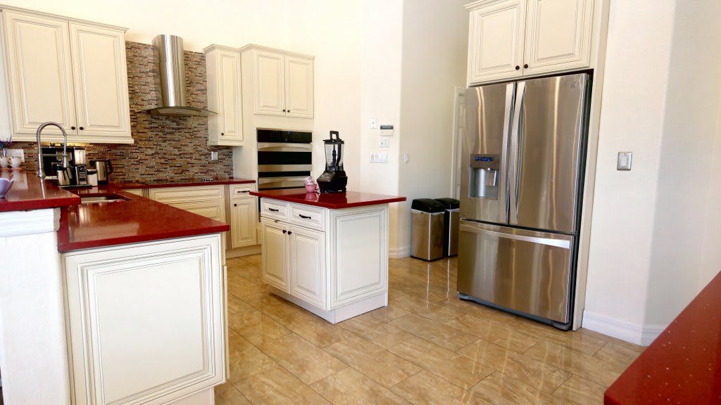 A modern kitchen with stainless steel appliances and red countertops.