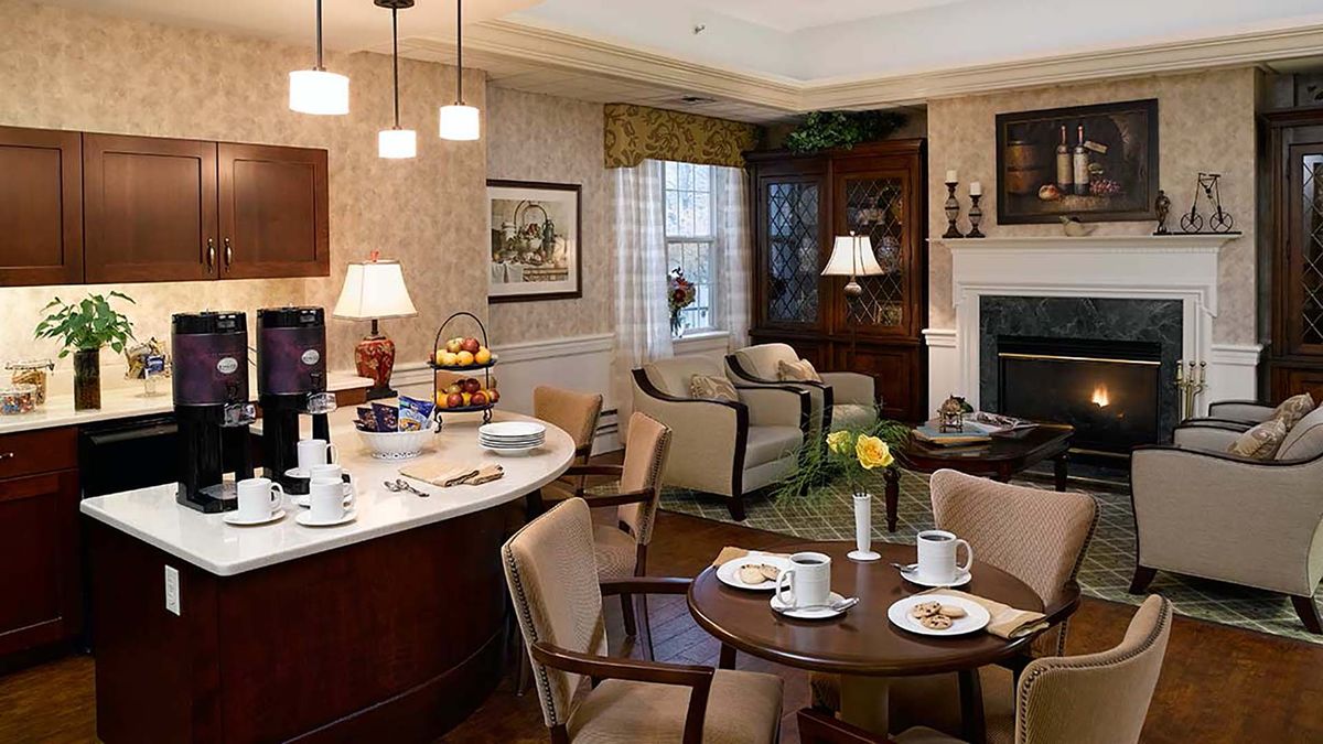 A cozy living room with a dining area featuring traditional decor and warm lighting.
