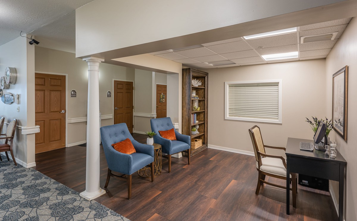 A cozy room with blue chairs, a bookshelf, and wooden flooring.