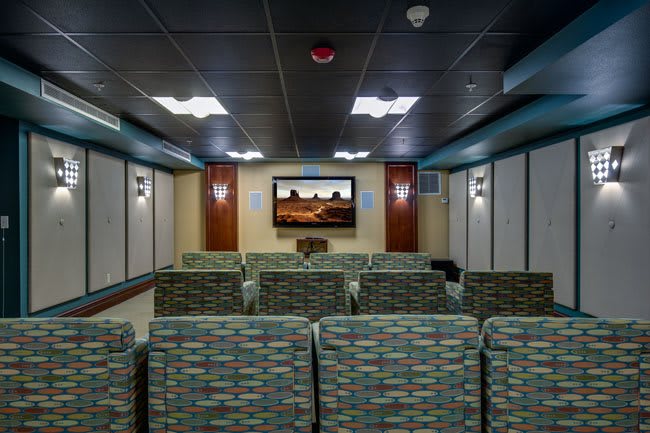 A small movie theater with patterned seating and a large screen.