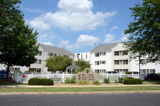 A view of a residential building with neatly landscaped grounds under a partly cloudy sky.