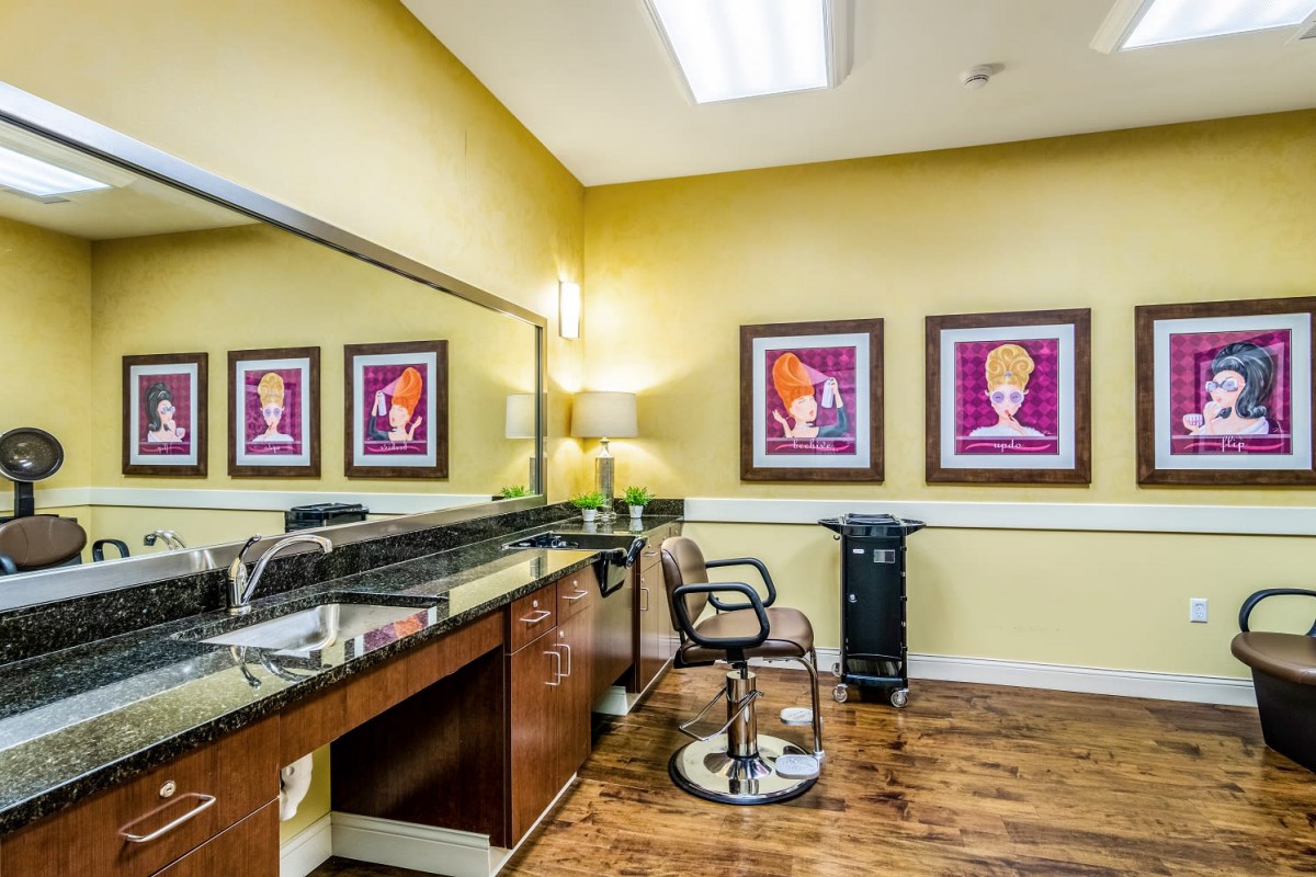 A brightly lit salon with a haircut station, featuring stylish chairs and vibrant artwork on yellow walls.