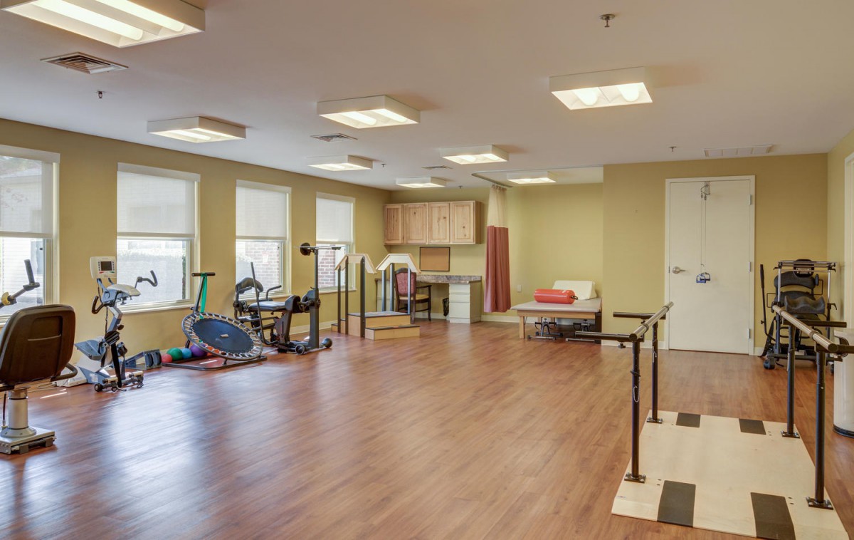 A therapy room equipped with various exercise equipment for rehabilitation and physical therapy.