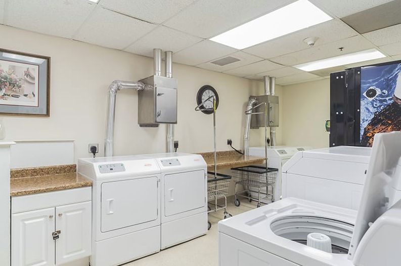 A clean and organized laundry room featuring multiple washing machines and dryers.