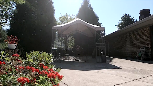 A tranquil outdoor stage surrounded by lush greenery and vibrant flowers.