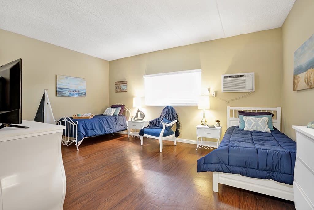 A cozy bedroom with two twin beds, blue bedding, and wooden floors.