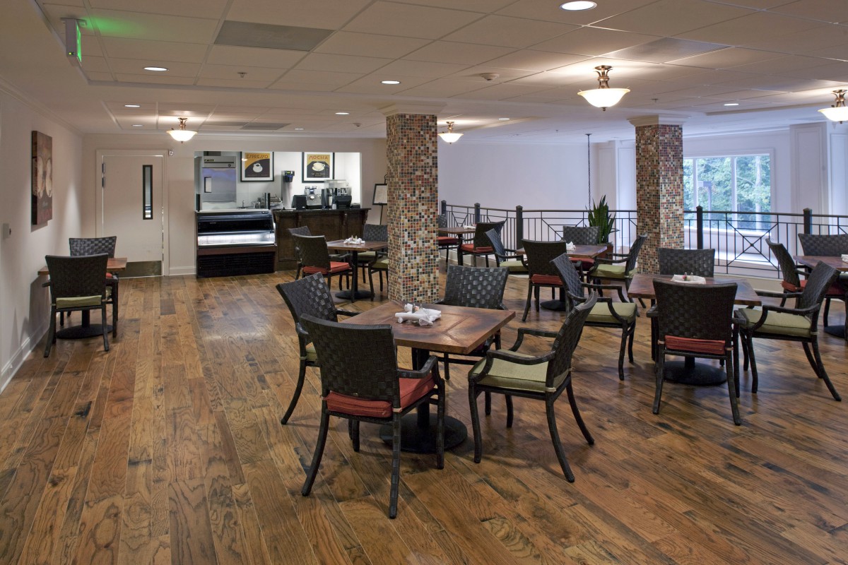 A spacious dining area with multiple tables and chairs on a wooden floor.
