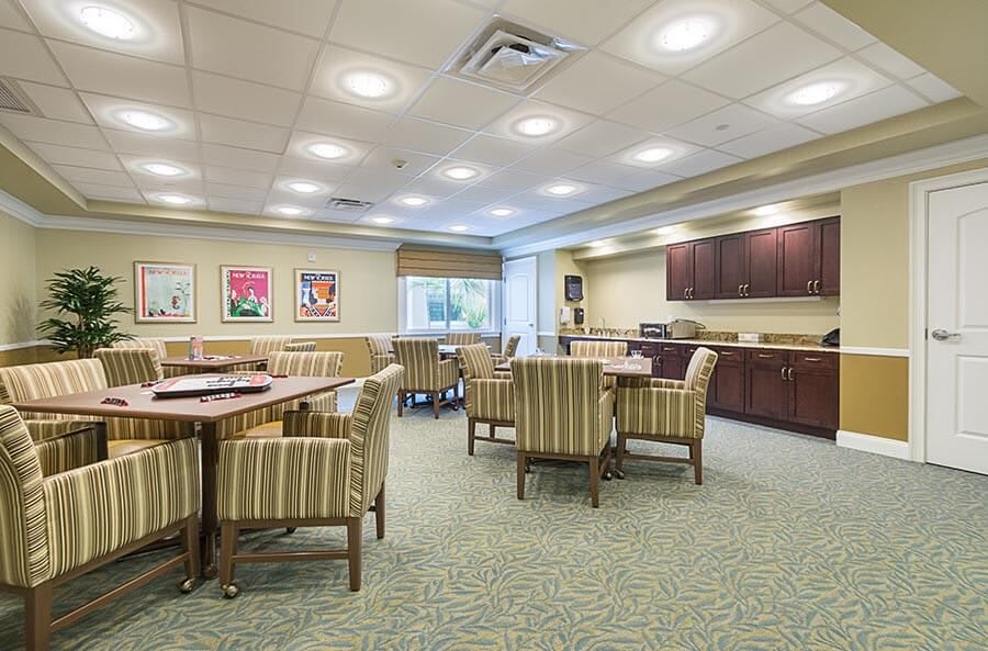 A well-lit conference room featuring multiple tables and striped chairs, decorated with artwork on the walls.