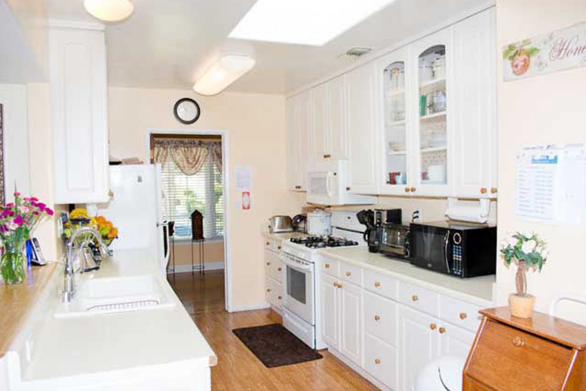 A bright, modern kitchen with white cabinets and a wooden floor.