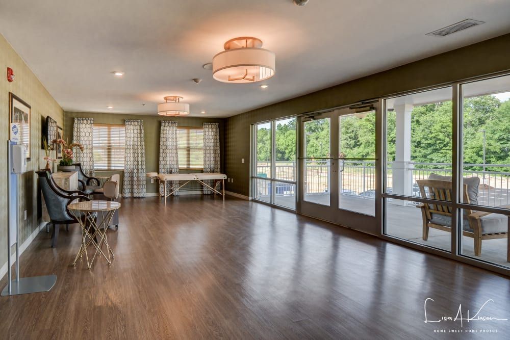 A spacious dining room with wood flooring, large windows, and elegant chandeliers.