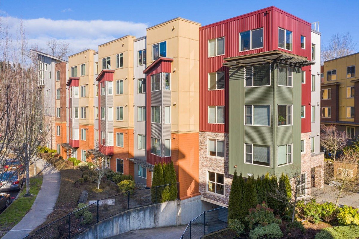 A colorful apartment building with multiple stories, featuring various shades of green, red, and beige in an urban setting.