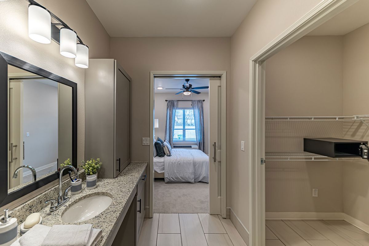 A modern bathroom leads into a bedroom, featuring elegant lighting and decor.