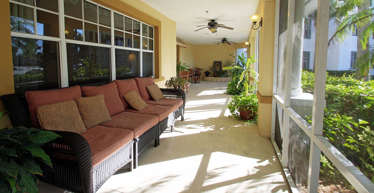 A sunlit porch with comfortable seating and plants, creating a relaxing atmosphere.