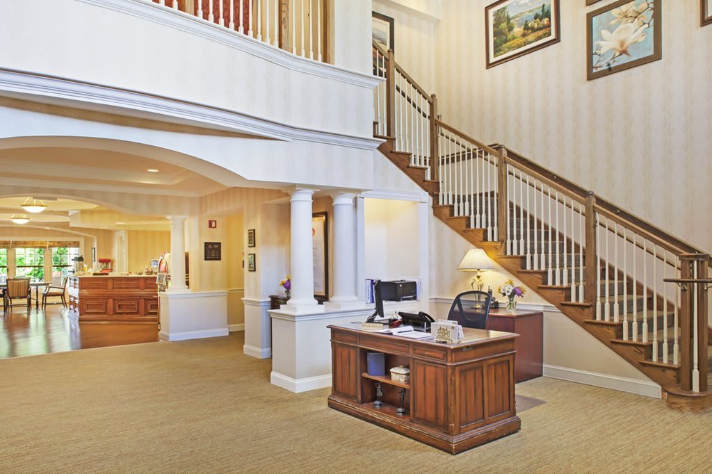 A welcoming office lobby with a wooden reception desk and elegant staircase.