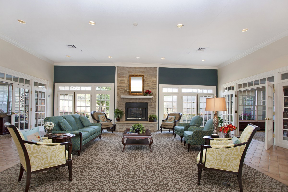 A spacious living room with sofas, armchairs, and a central fireplace.