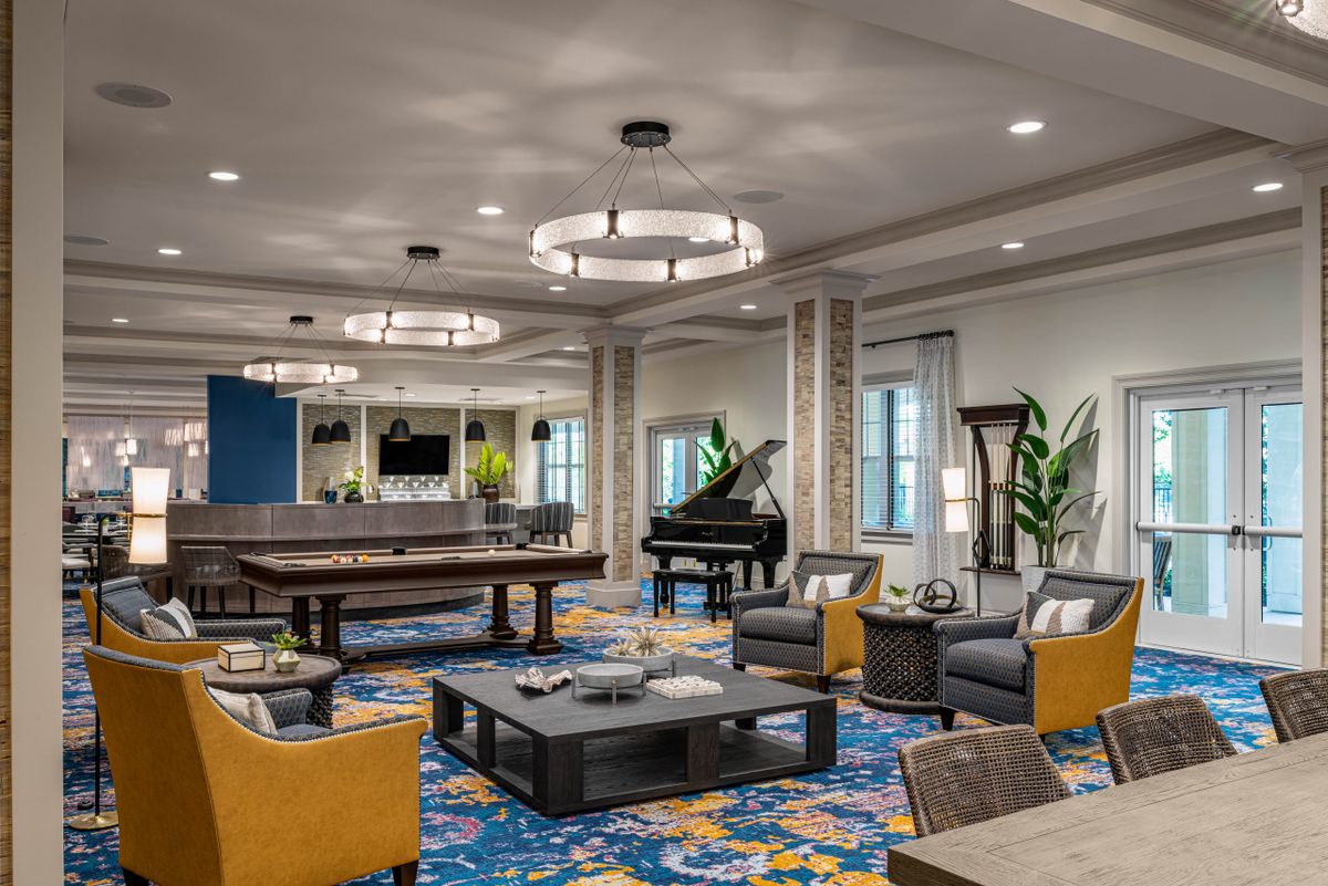 A luxurious lounge featuring a grand piano, pool table, and elegant seating with art deco elements.