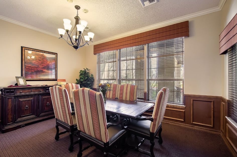 A cozy dining room with a large table, upholstered chairs, and a chandelier.