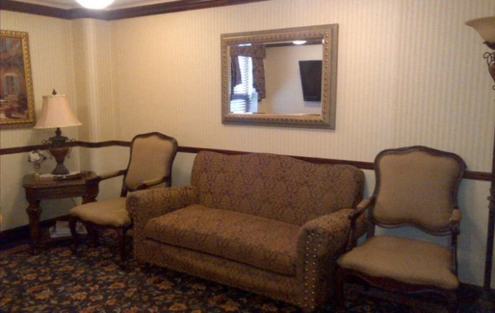 A cozy living room setup featuring a sofa, two armchairs, and a large mirror.