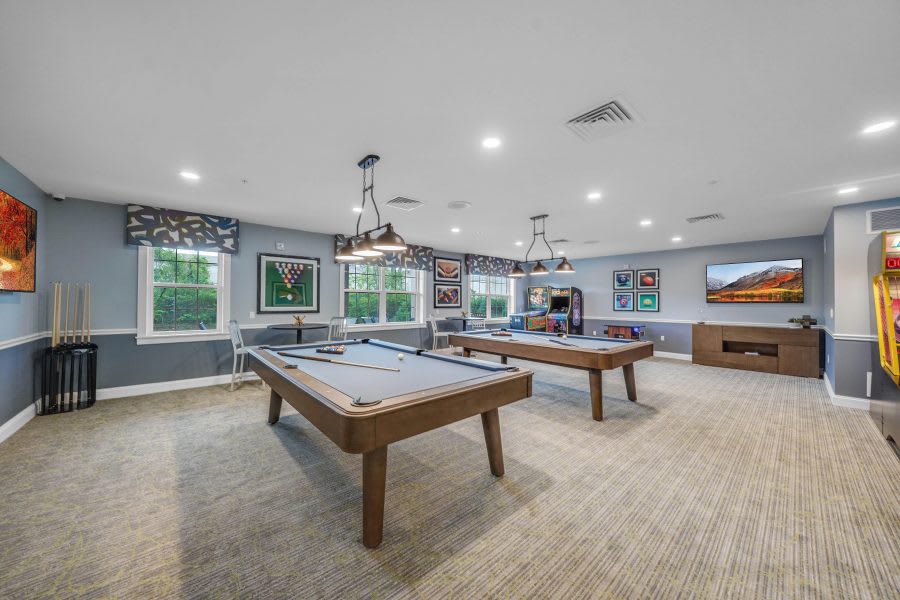 A spacious game room featuring multiple pool tables and cozy lighting.