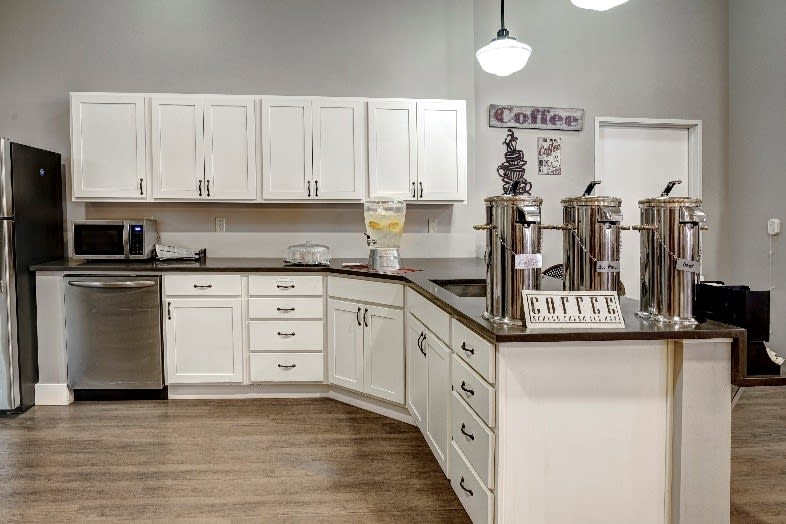 A modern kitchen with white cabinets and a dedicated coffee station on the countertop.