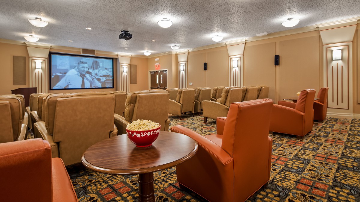 A cozy home theater with comfortable seating and a projector screen, featuring a bowl of popcorn on a side table.