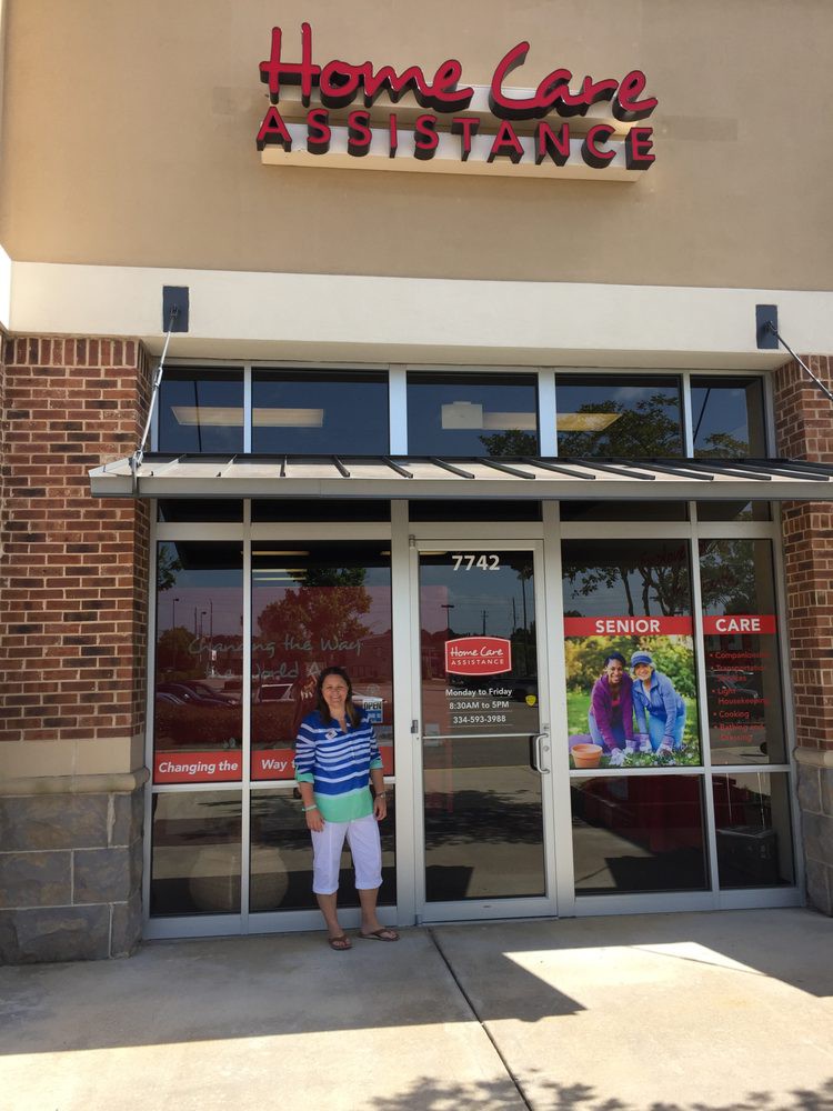 A person standing in front of a storefront entrance on a sunny day.