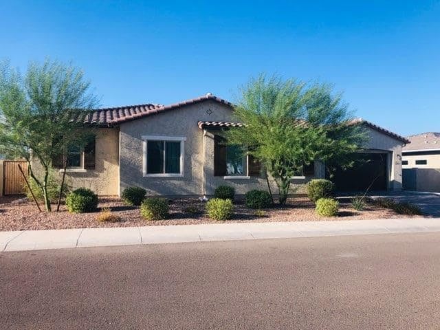 A suburban house surrounded by desert landscaping on a sunny day.