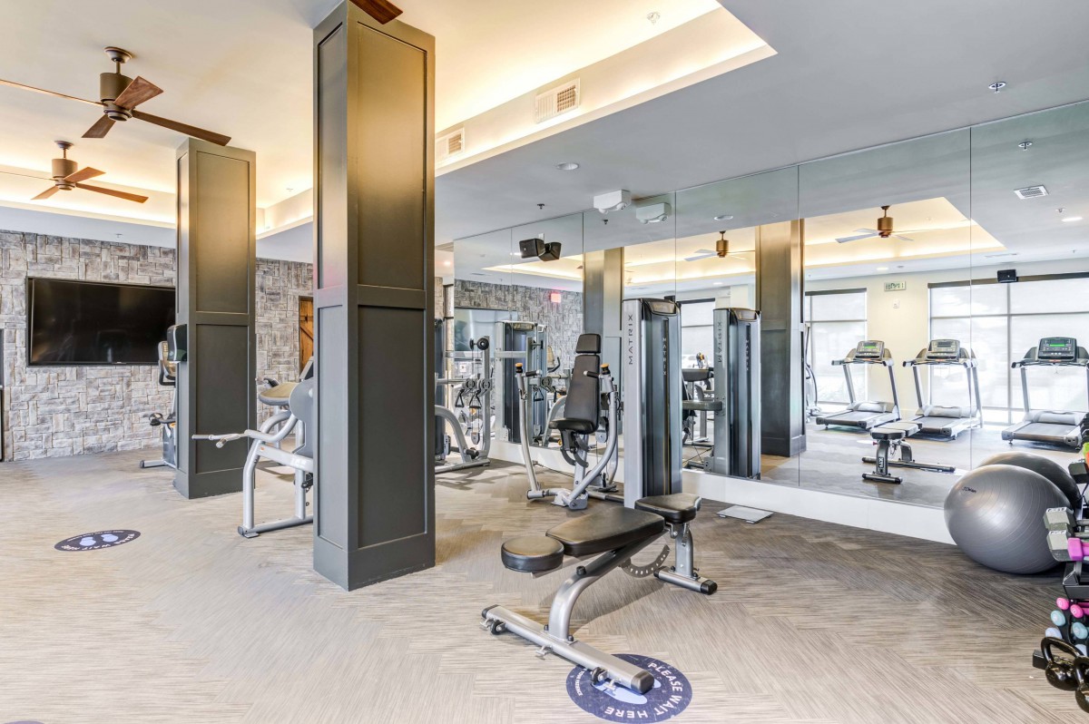 A modern gym with various exercise equipment and mirrors.