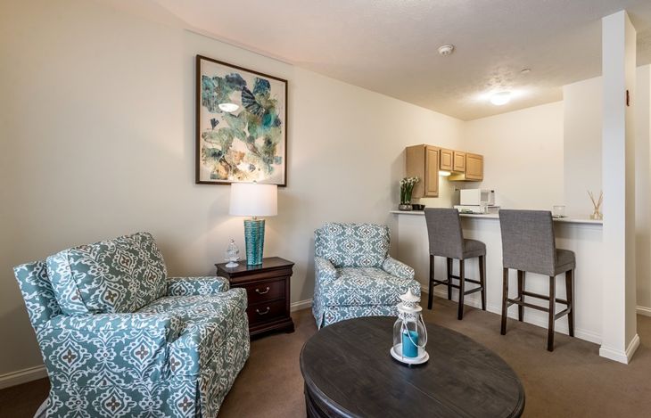 Cozy living area with patterned chairs and a view into the kitchen.
