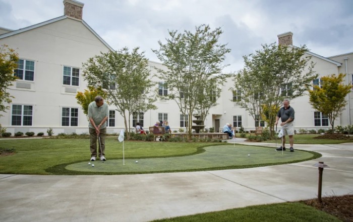 People enjoying a game of golf on a putting green in front of a building.