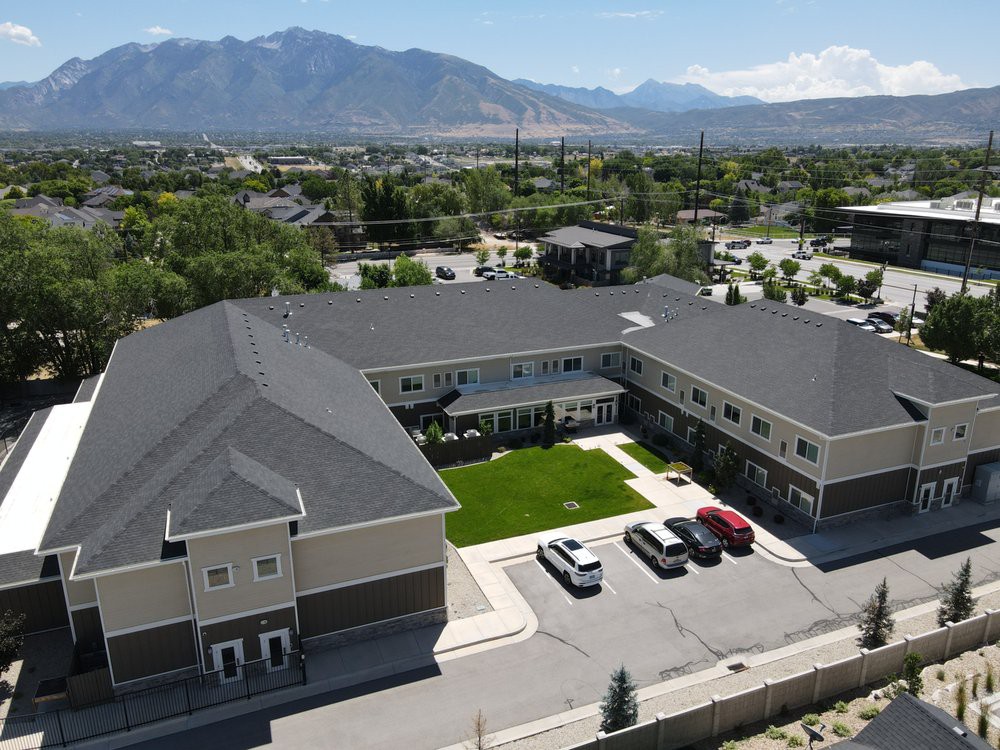 Aerial view of a residential building with a parking lot and mountains in the background.