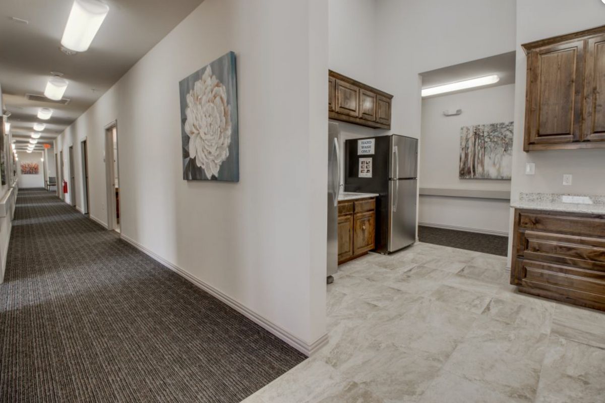 A modern hallway with a kitchenette and artwork on the walls.