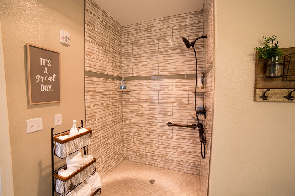 A modern walk-in shower with beige tiles and a wall-mounted showerhead.