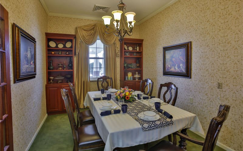 A traditional dining room with an elegantly set table and a chandelier.