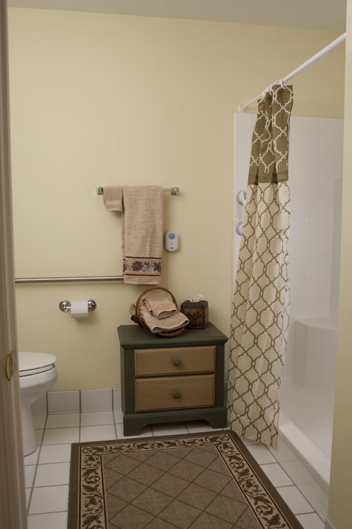 A neatly organized bathroom with a patterned shower curtain, a small cabinet, and decorative towels.